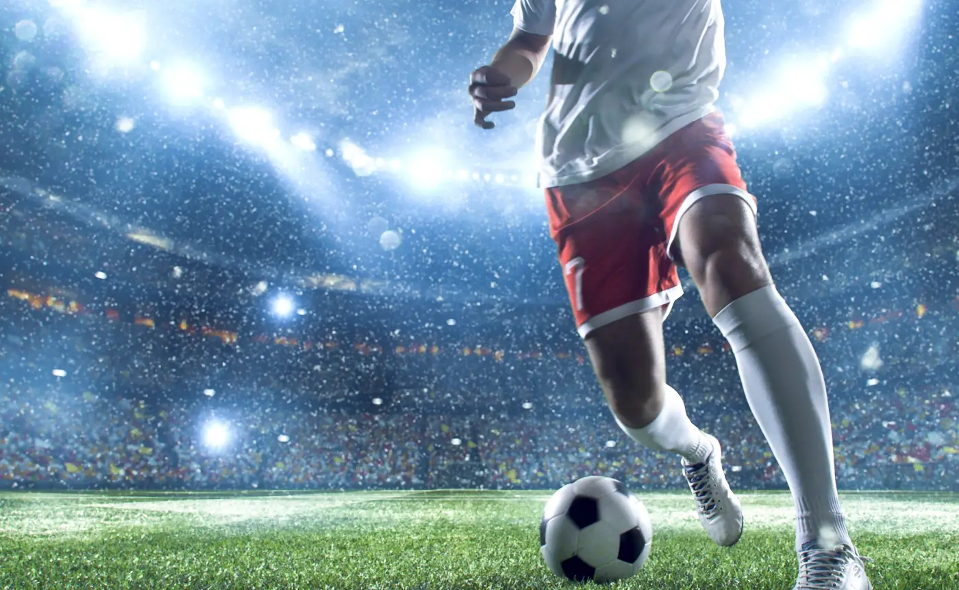 Lit-up sports stadium at night with crowd atmosphere